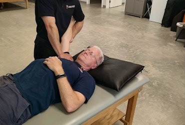 Physical therapist providing hands-on treatment to a patient lying on a therapy tablePhysical therapist providing hands-on treatment to a patient lying on a therapy table