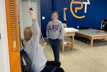 Physical therapist guiding a patient through a resistance band shoulder exercise