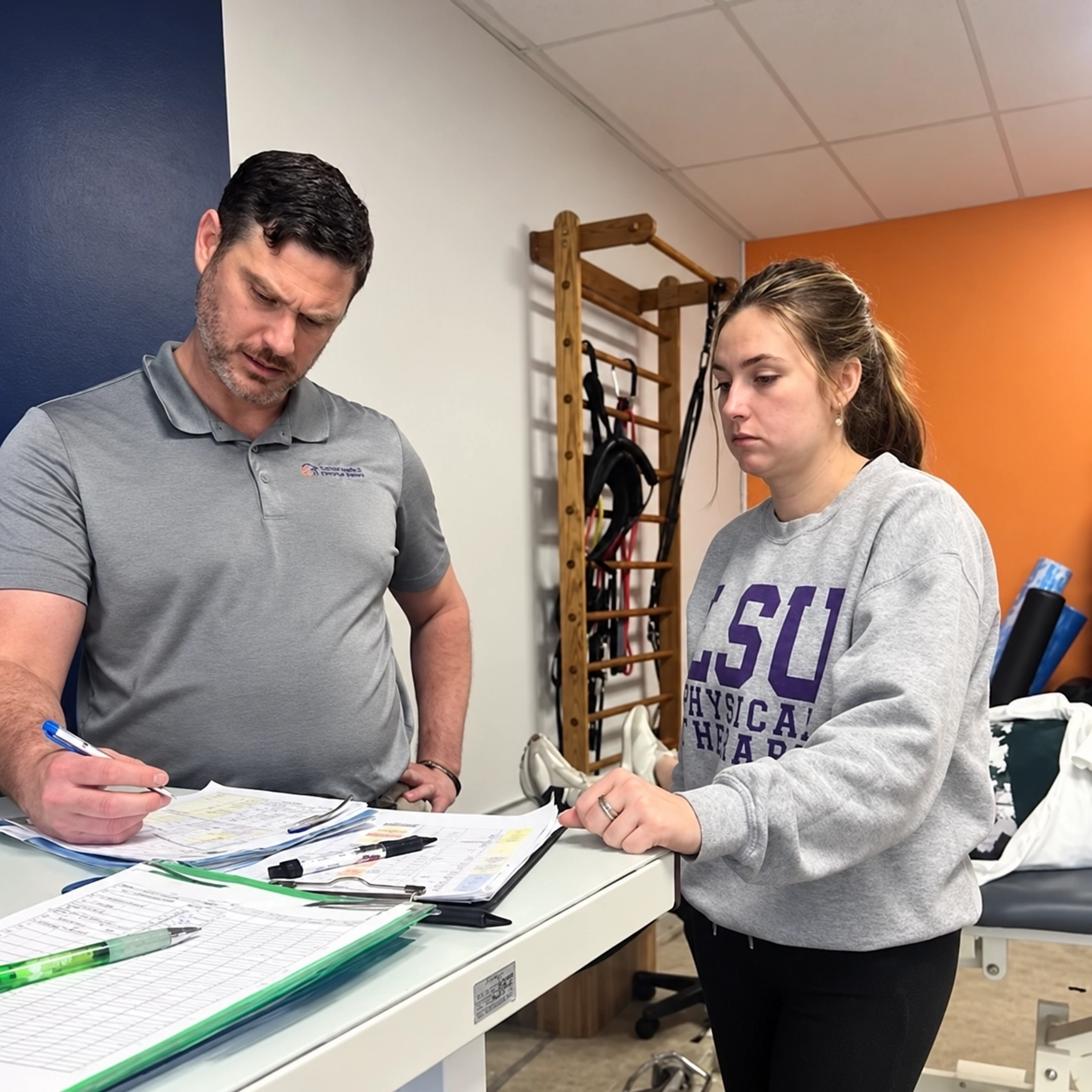 Physical therapy staff members reviewing paperwork together inside a treatment room