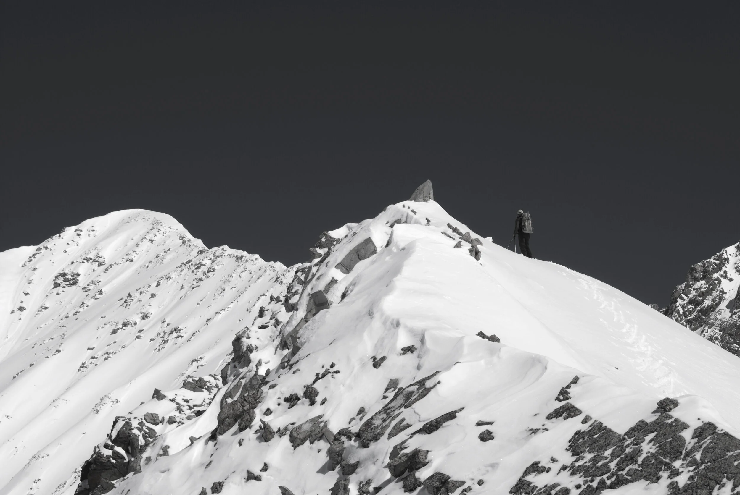A person standing on a snow-covered mountain ridge