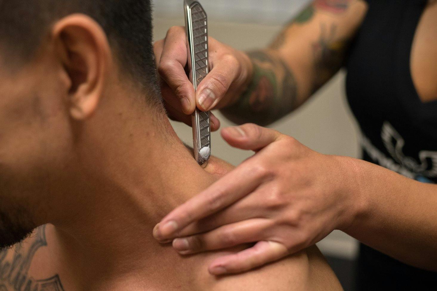 A physical therapist treating a patient's neck with an instrument