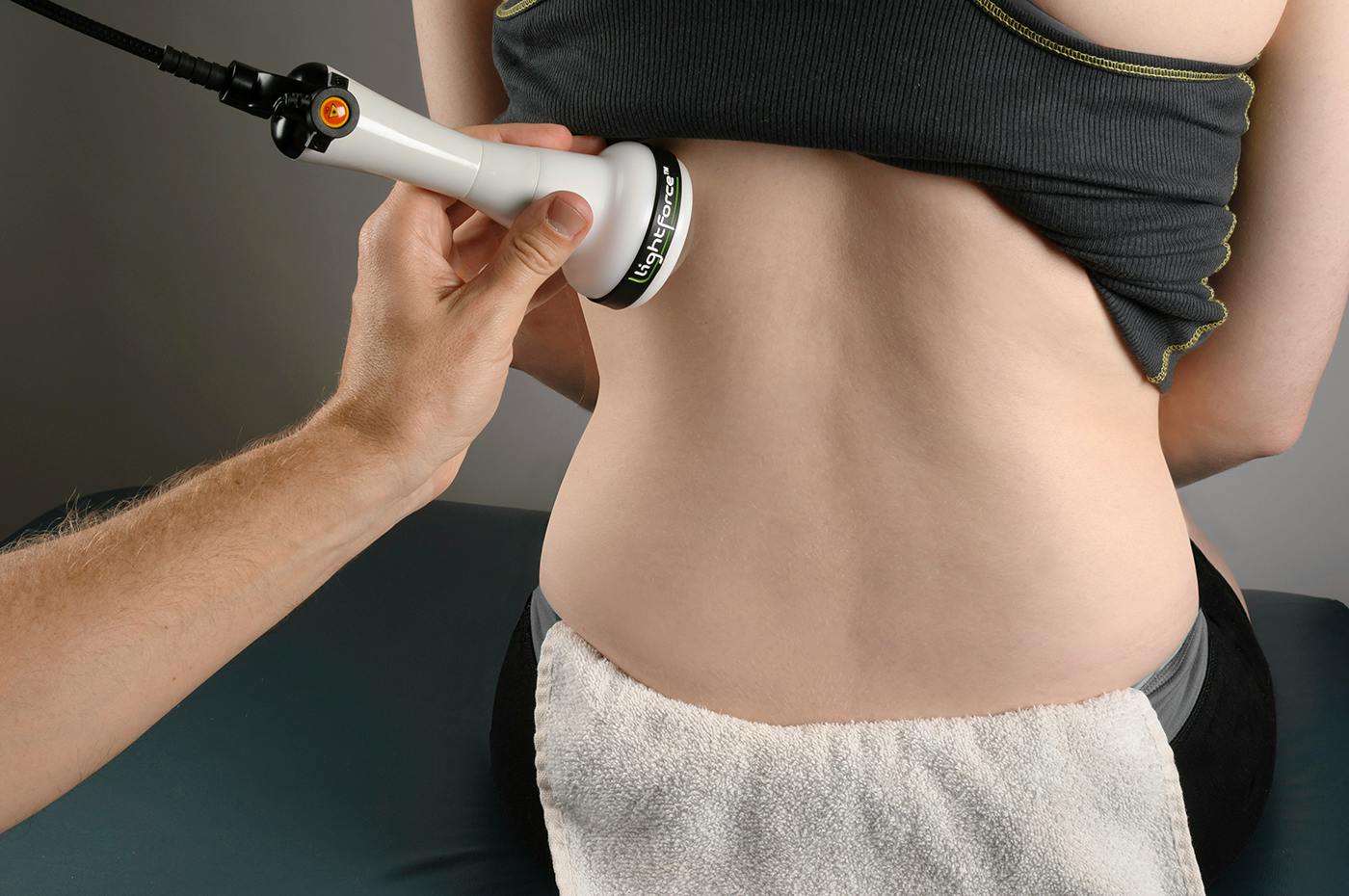 A laser applicator held against a patient's low back