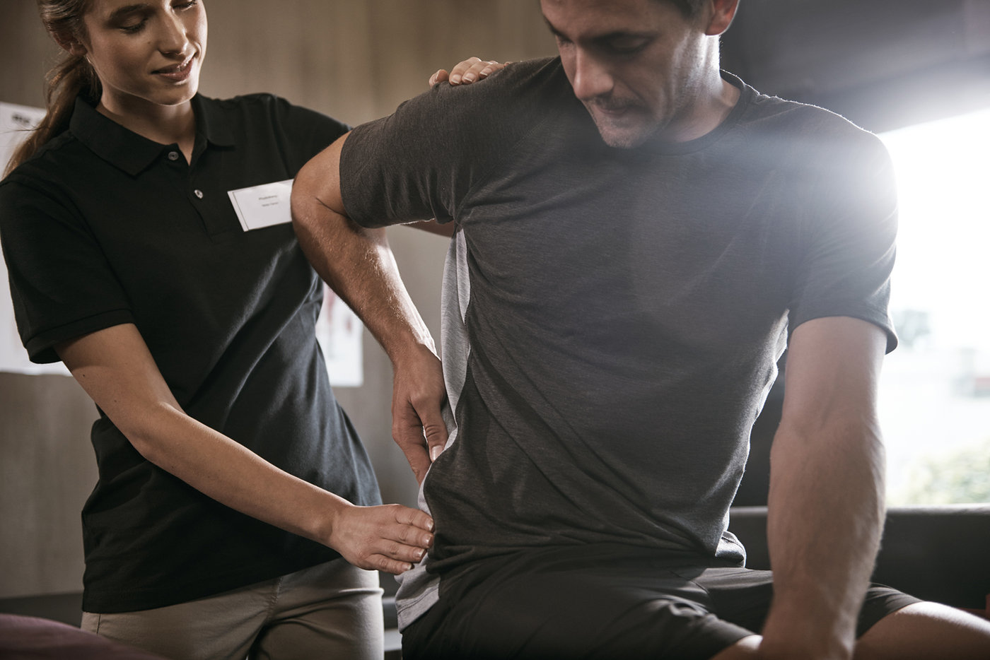A physical therapist checking a patient’s lower back during an evaluation