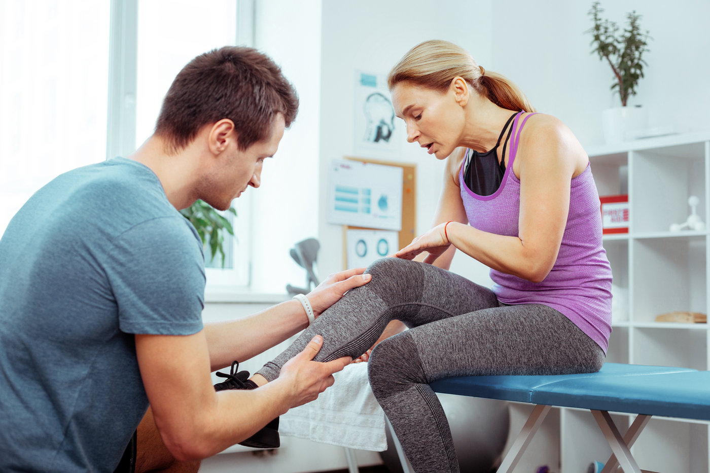 A physical therapist examining a patient’s knee and leg