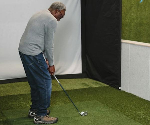 A patient lining up a putt at the golf simulator in the PAR clinic