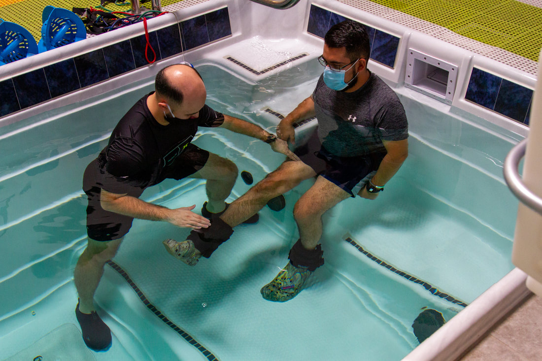 A physical therapist guiding a patient through a leg exercise in the aquatic therapy pool