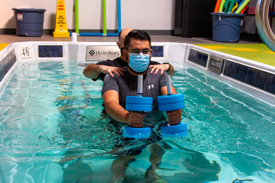 A patient exercising in the aquatic therapy pool holding dumbbells