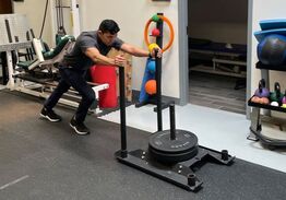 A patient pushing a weighted sled during a rehab session