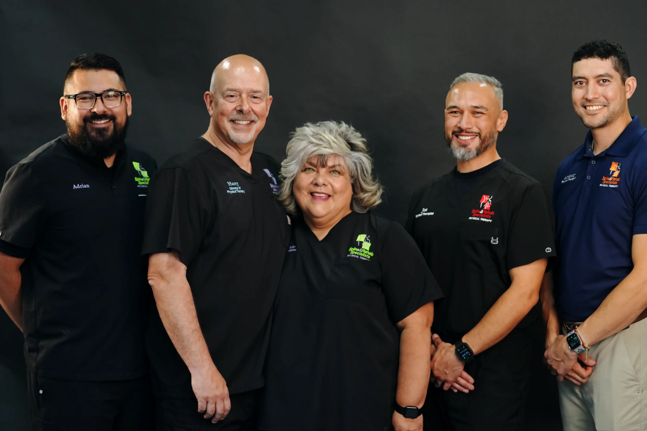 Five members of the Spine & Rehab Specialists team standing together in clinic scrubs and polo shirts