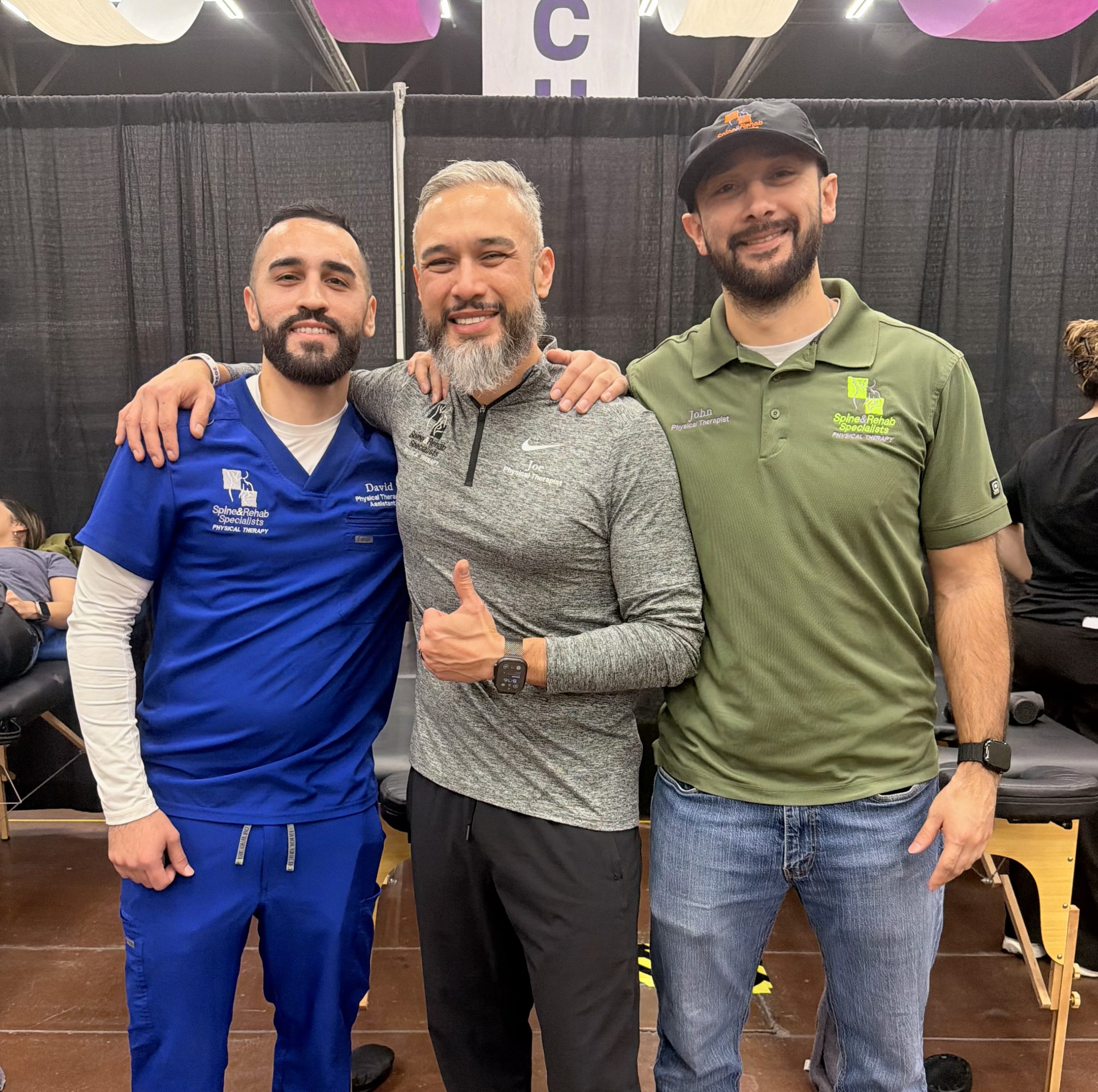 Three men posing together with thumbs up in the clinic