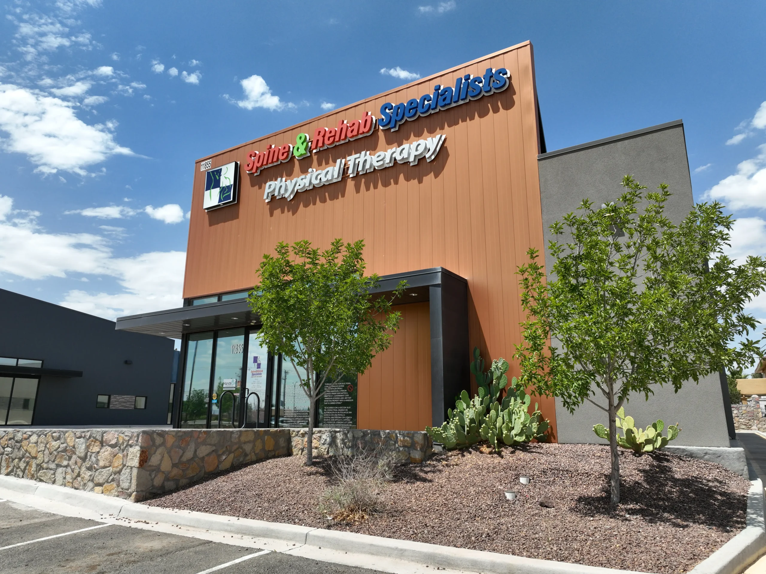 The Spine & Rehab Specialists clinic on Physicians Drive: a modern building with a copper-toned wall and the practice sign above the entrance